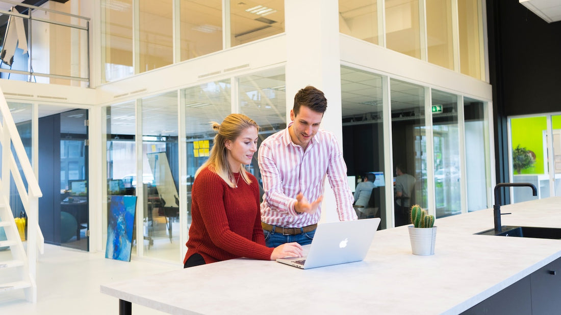 man and women looking at laptop in office