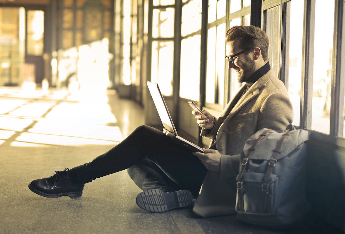 man using laptop and cellphone to receive funds