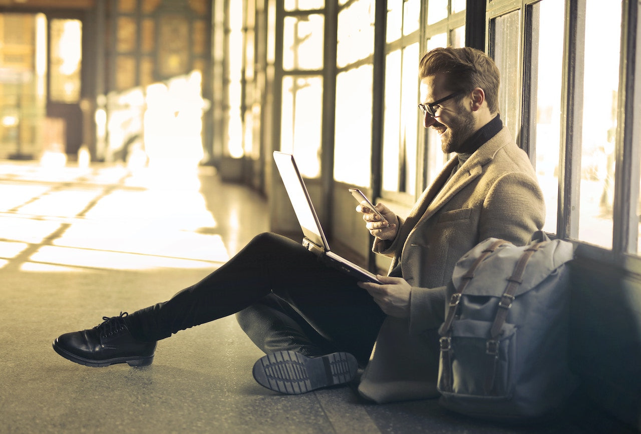man using laptop and cellphone to receive funds